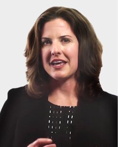 A woman with shoulder-length brown hair wearing a black blazer is speaking, with a neutral light gray background.