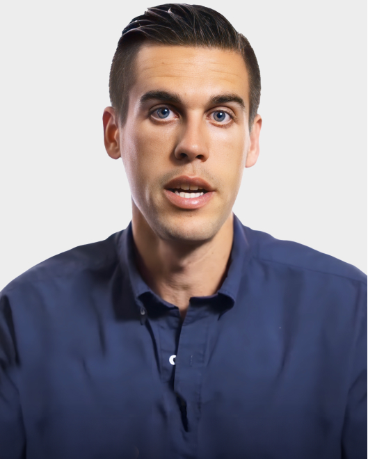 A man with short dark hair, wearing a navy blue button-up shirt, looks forward with a neutral expression against a plain white background.