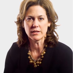 A woman with shoulder-length wavy hair wearing a black top and a gold necklace, looking forward against a plain background.