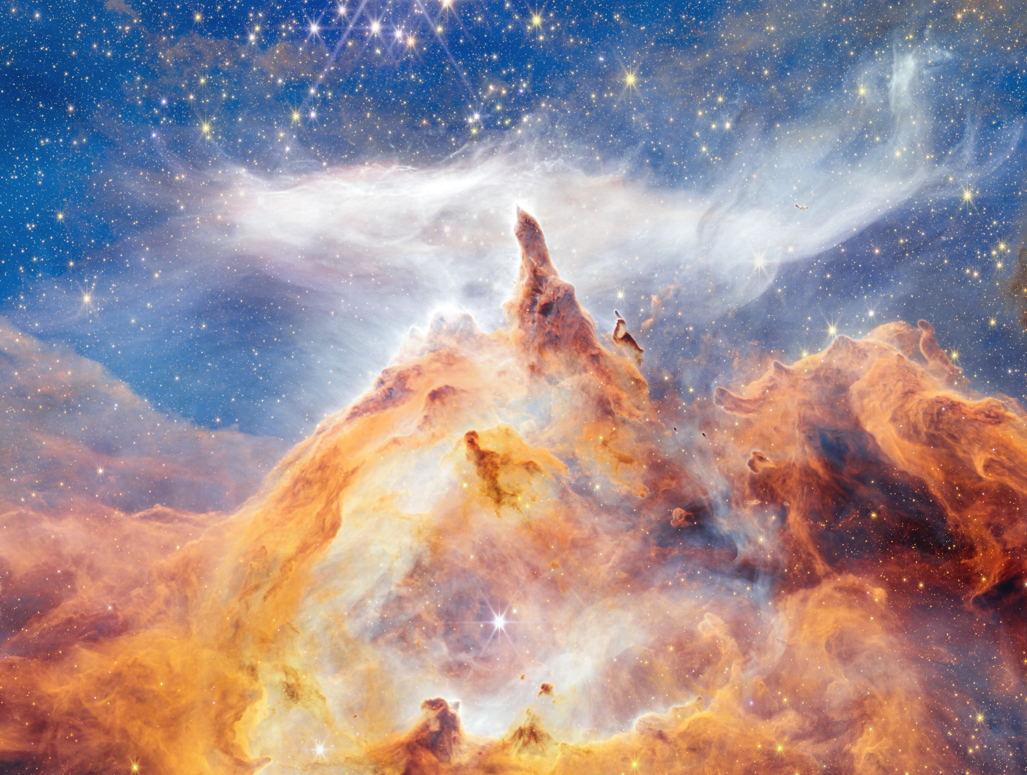 Colorful nebula with swirling orange gas and dust clouds against a blue, star-filled background in outer space, as captured by JWST and Hubble near the Pismis 24 star cluster.