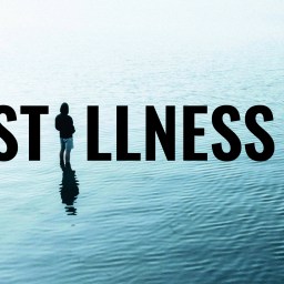 A person stands alone on calm water with the word "STILLNESS" in bold letters over the scene.