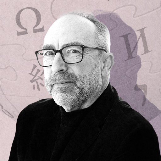 A middle-aged man with glasses and a beard, resembling Jimmy Wales, poses in front of a light-colored background featuring Wikipedia's globe logo and various language characters.