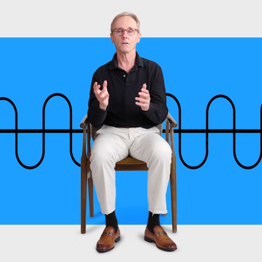 An older man sits on a chair gesturing with his hands in front of a blue background featuring a black sinusoidal waveform and an arrow.
