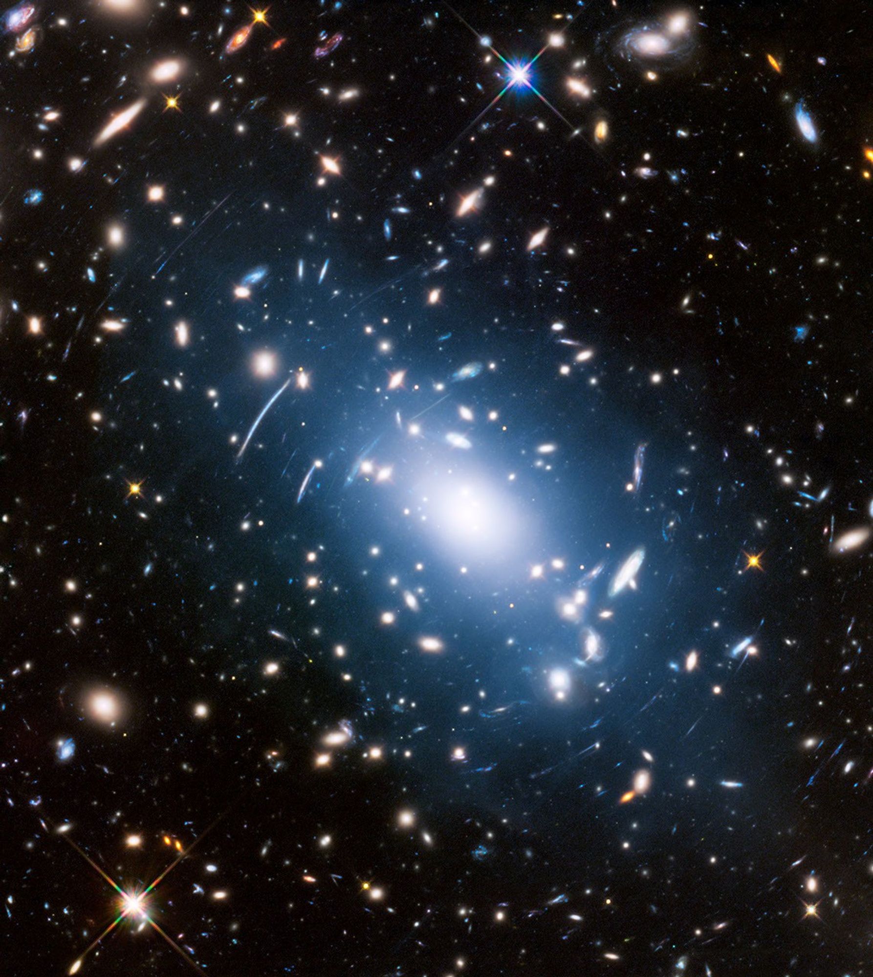 A bright galactic cluster with numerous galaxies, including fascinating jellyfish galaxies and stars, is surrounded by a blue glow and light distortions against a dark background.