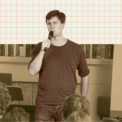 A man holding a microphone speaks to an audience in front of a bookshelf and a display with logos, including "Roots of Progress Institute" and "Big Think.