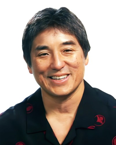 A man with short dark hair and a black shirt smiles at the camera against a white background.