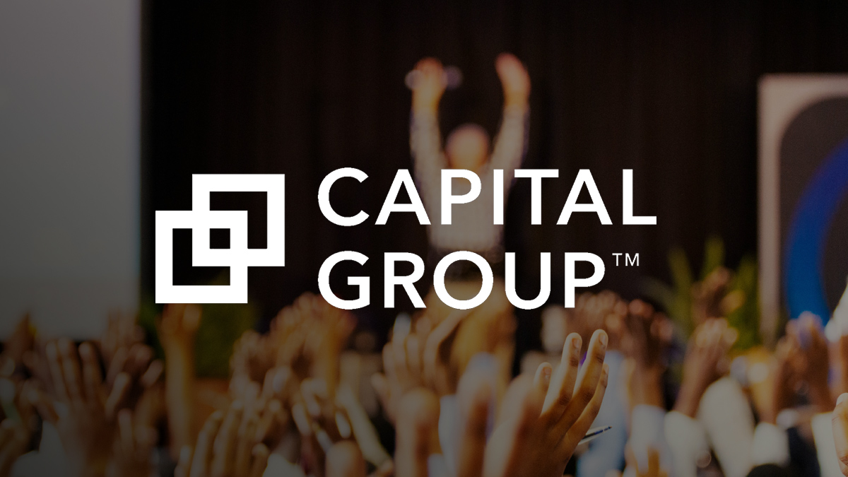The Capital Group logo displayed over a blurred background of raised hands and a standing person on stage.