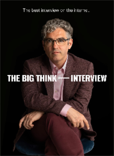 A man with curly gray hair and glasses sits with hands clasped, wearing a maroon jacket and pink shirt. Text reads “THE BIG THINK INTERVIEW” and “The best interview on the inter...”.