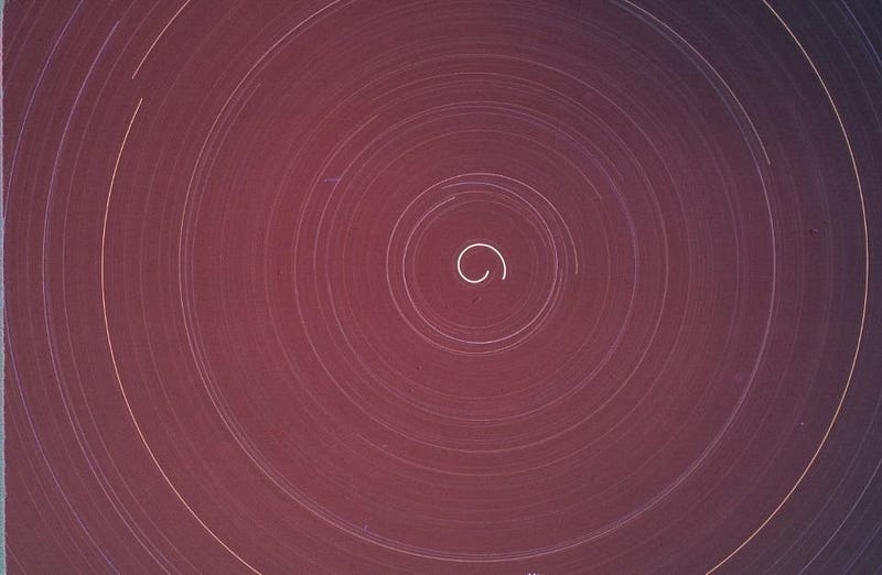 Long-exposure photo of star trails forming concentric circles in the night sky, centered around the north celestial pole.