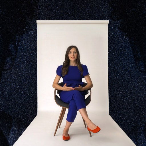 A woman in a blue outfit and red heels sits on a chair in a studio with a white backdrop, flanked by stylized images of a person's face looking at a phone.