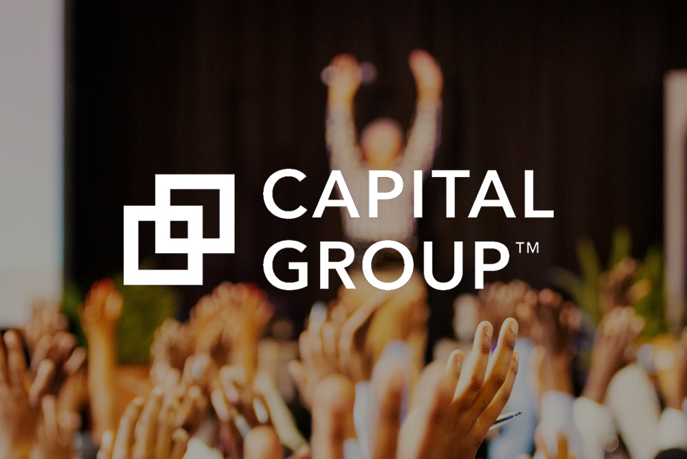 Capital Group logo overlaid on a blurred image of raised hands in an audience, with a person standing on stage in the background.