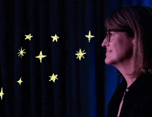 A woman with glasses stands in profile against a dark background with illustrated yellow stars scattered beside her.