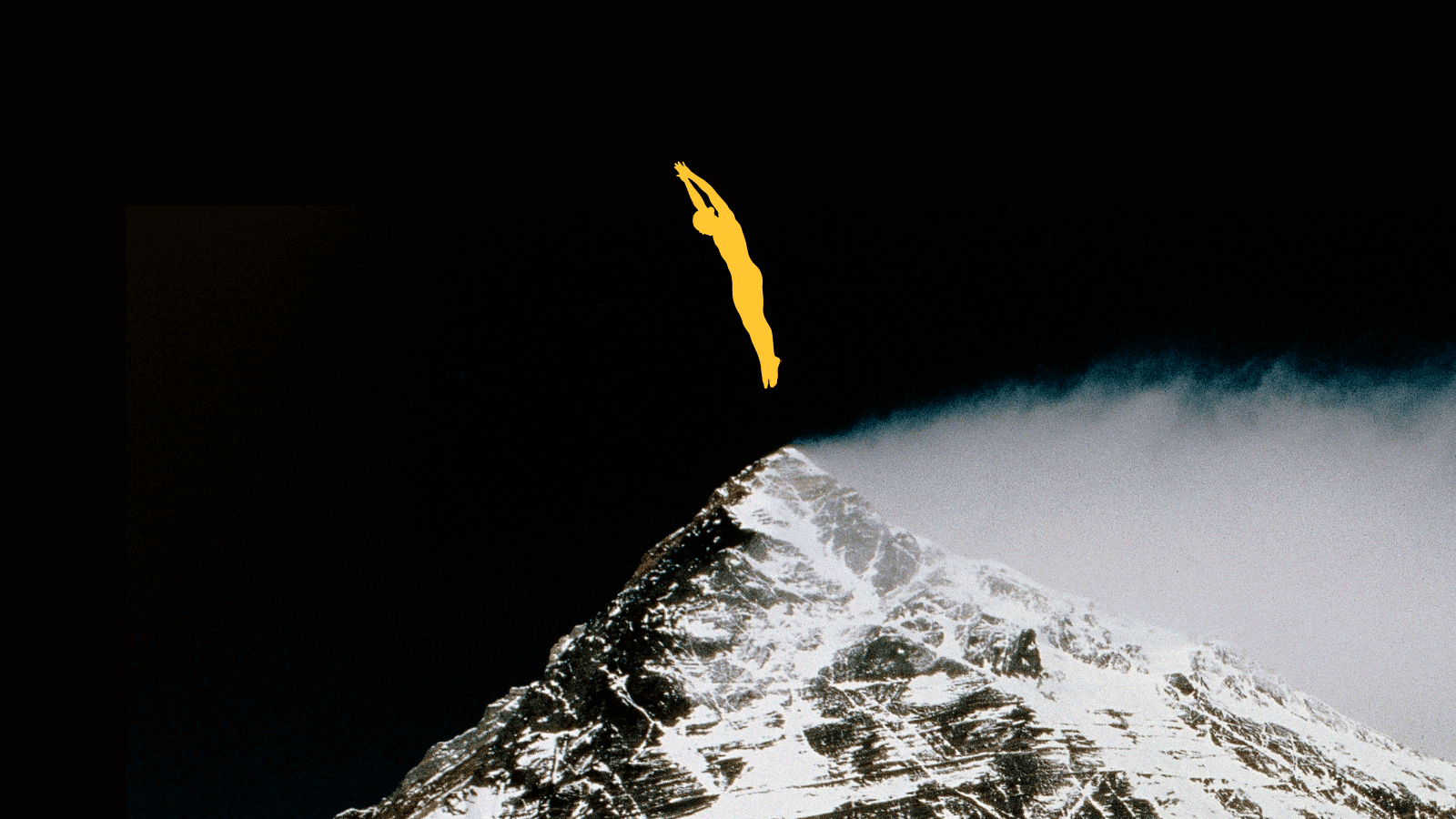 A yellow silhouette of a person dives above the snow-covered peak of a mountain against a dark sky.