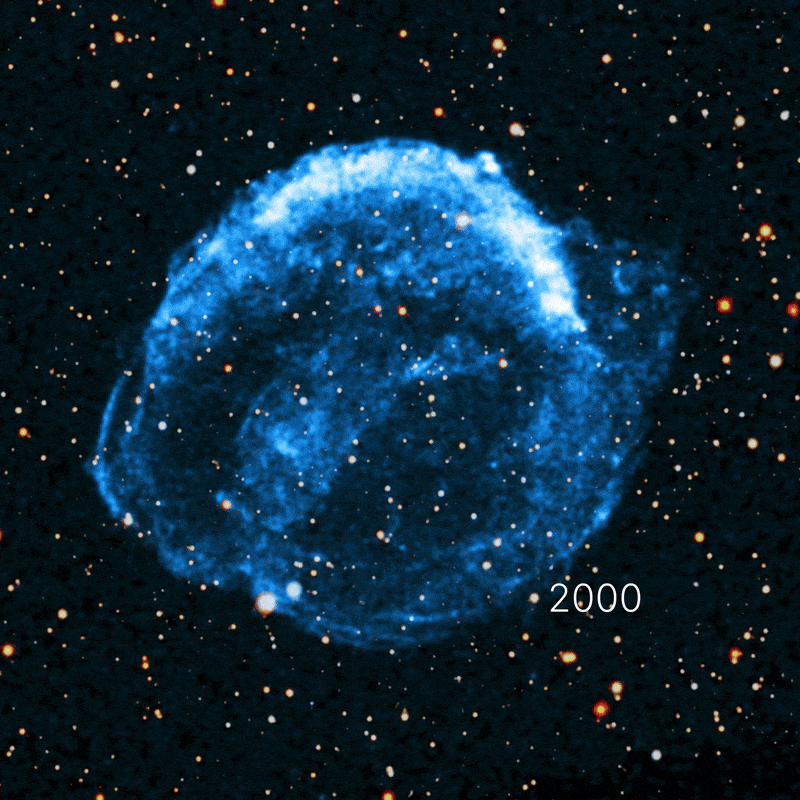 A blue-hued supernova remnant glows against a star-filled black background, captured by NASA Chandra 25 years after Kepler's supernova, with the number "2000" visible on the right side of the image.