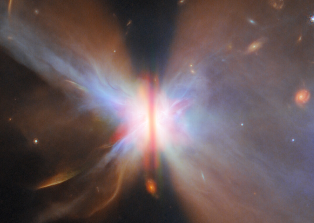 A colorful nebula with a bright center and symmetrical, wing-like clouds of gas and dust extends outward in space, as seen in a JWST reveal that uncovers stars and galaxies in the universe beyond.