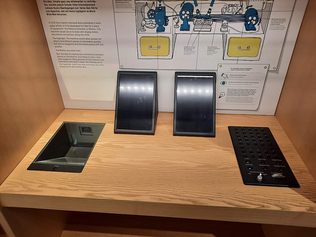 A display with two touchscreen panels, a control panel with buttons and dials, and an information panel with diagrams and text, all set on a wooden surface.
