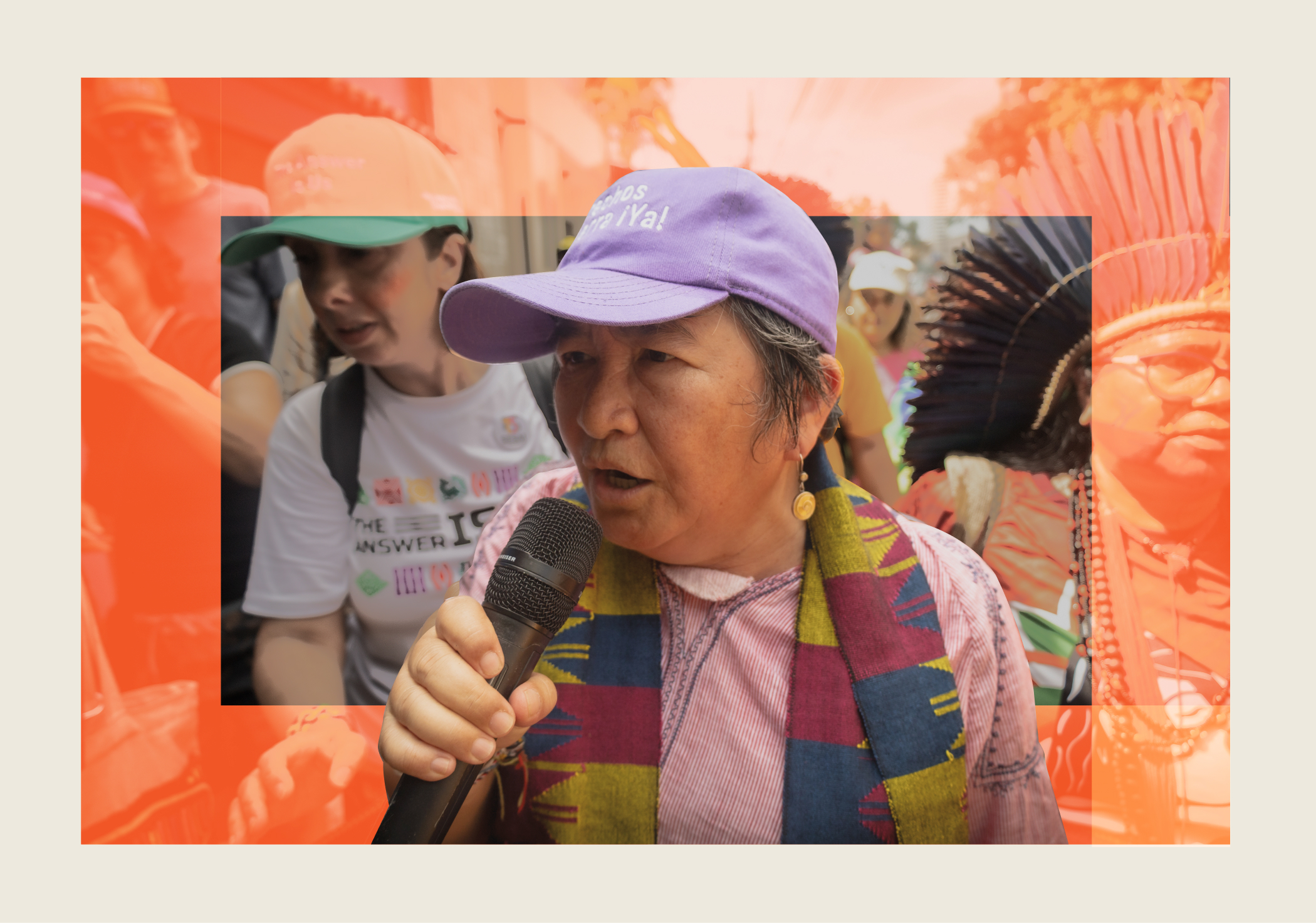 An older woman wearing a purple cap holds a microphone, speaking at a protest or gathering, with other people and an overlay of orange graphics in the background.