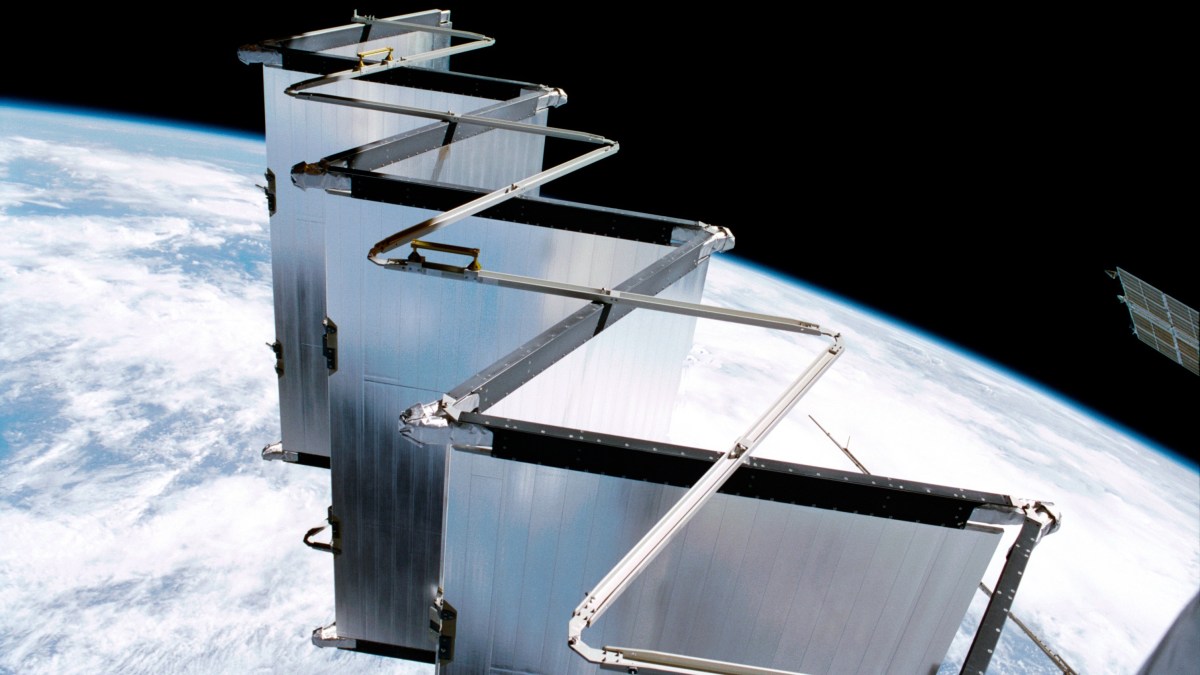 A satellite with extended accordion-like solar panels or reflectors, possibly supporting AI data centers in space, orbits above Earth, with the planet’s surface visible in the background.