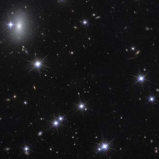 A view of a star-filled night sky with numerous bright stars and distant galaxies, including Hubble-dark galaxy formations, scattered across a dark background.
