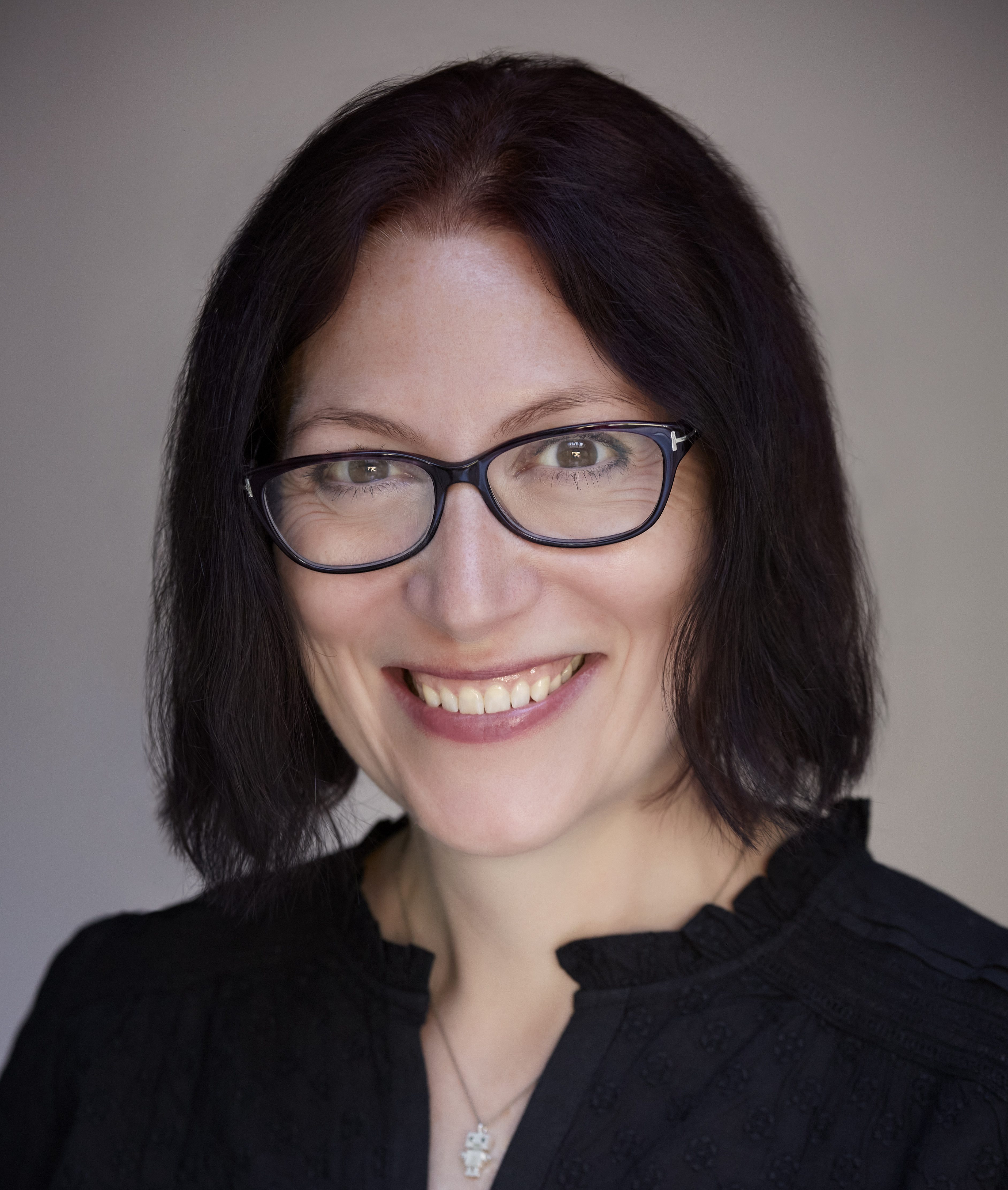 A woman wearing glasses and smiling.