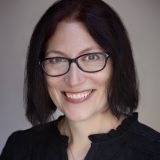 A woman wearing glasses and smiling.