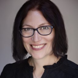 A woman wearing glasses and smiling.