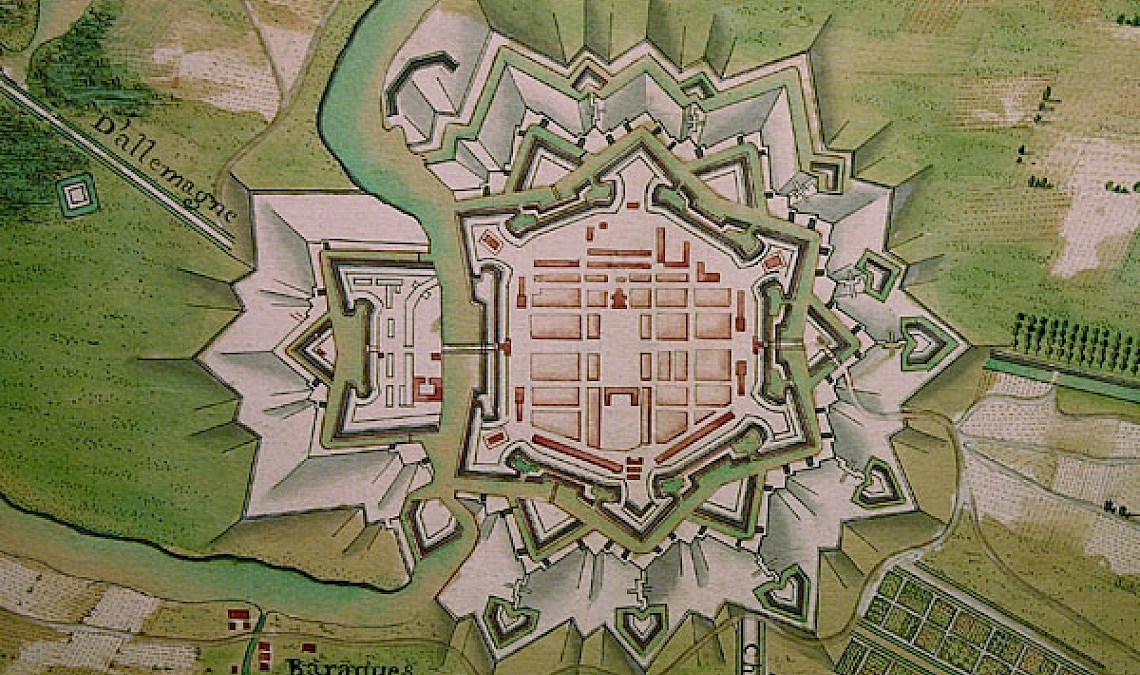 Historic map illustration of a star-shaped fortified city with surrounding moat, labeled roads, and buildings visible outside the city walls.