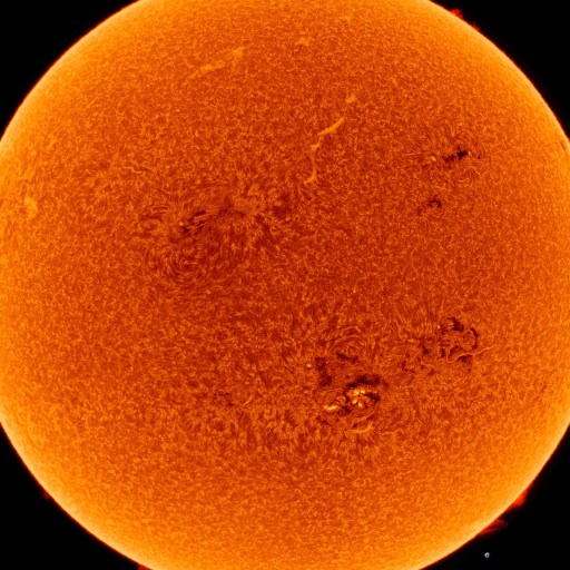 A detailed orange image of the Sun shows its surface texture and sunspots, against a black background.