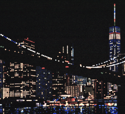 Night view of a city skyline with illuminated skyscrapers and a bridge, home to a self-healing power grid, all reflected in the water below.
