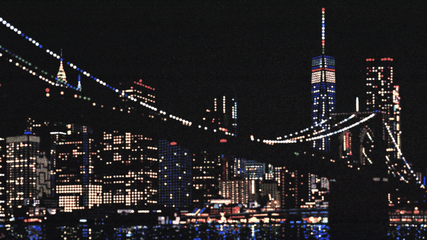 Night view of a city skyline with illuminated skyscrapers and a bridge, home to a self-healing power grid, all reflected in the water below.