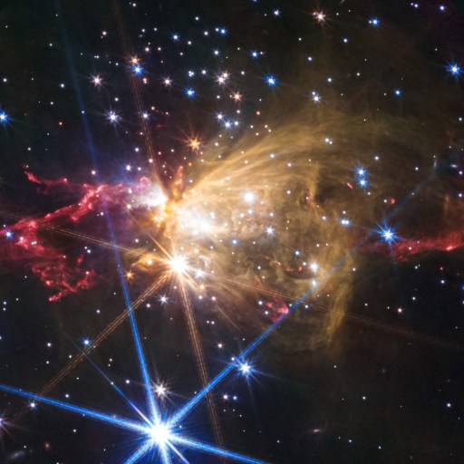 Colorful nebula with bright stars ignite glowing gas clouds in space, featuring red, yellow, and blue hues against a dark background.