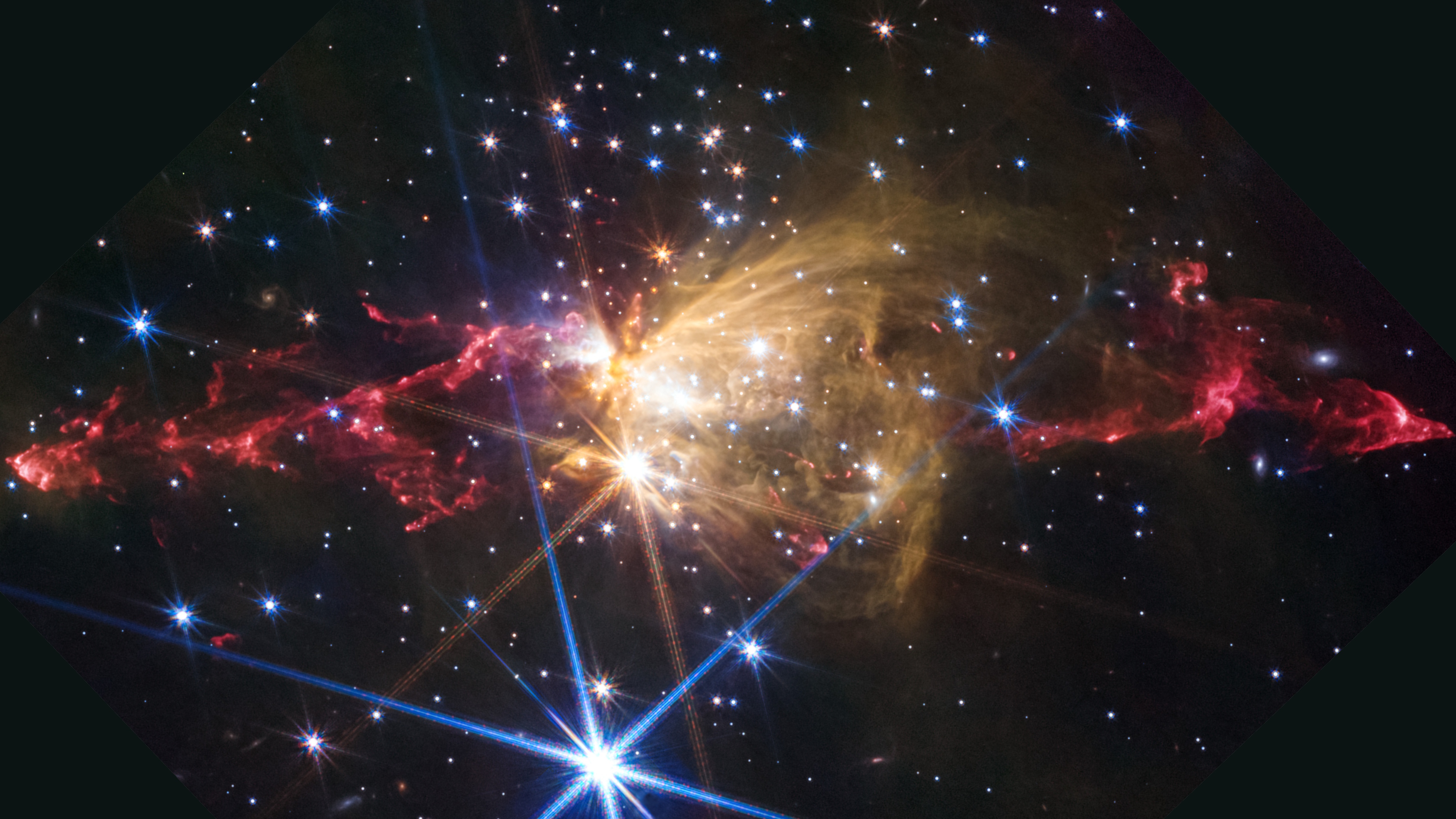 Colorful nebula with bright stars ignite glowing gas clouds in space, featuring red, yellow, and blue hues against a dark background.