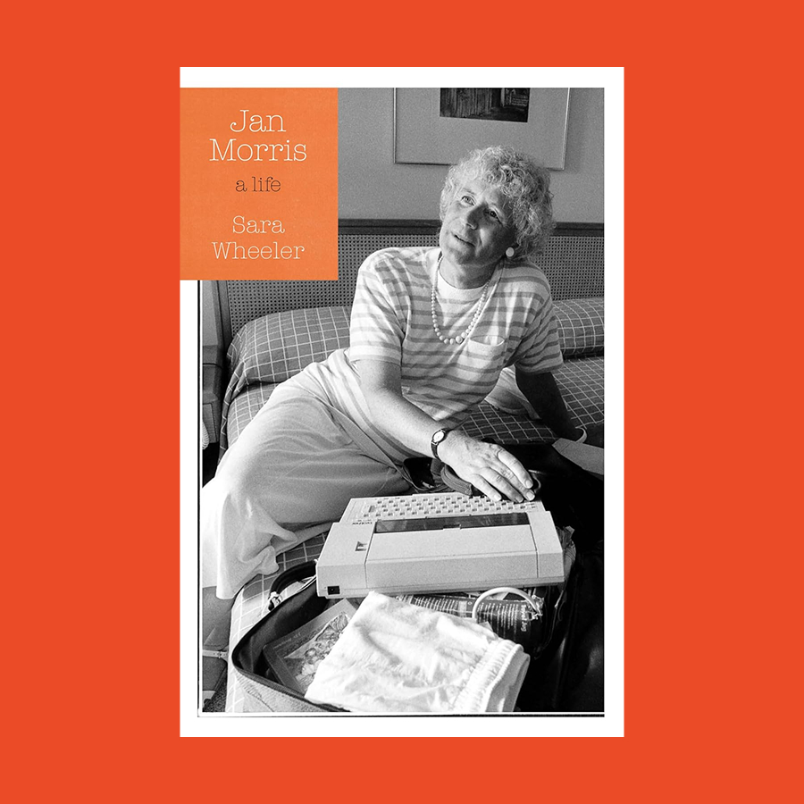 Black-and-white photo of Jan Morris, an older person seated on a bed, smiling with a typewriter in front. The book cover text reads: "Jan Morris, a life, Sara Wheeler.